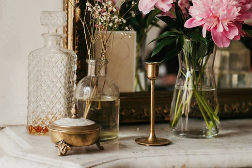 beautiful home decor for fall 2024 - glass bottles, brass candlestick, pink flowers - GearDen