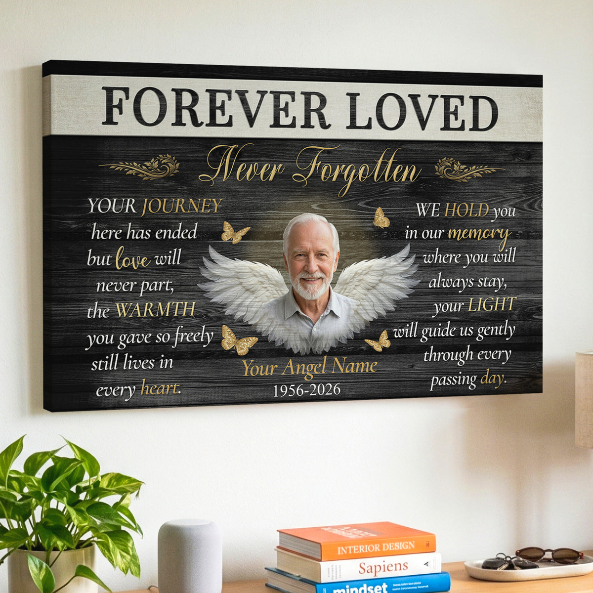 A personalized canvas wall art print with the text 'FOREVER LOVED' and 'Never Forgotten,' and a memorial verse featuring a photo of a smiling elderly man with angel wings, gold butterflies, and memorial text, displayed on a wall.